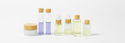 Glass cosmetic bottles with frosted and clear finish  bamboo caps and pump dispensers  suitable for perfumes  oils  sprays and care products.